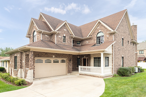 Oak Park, IL, USA - June 26, 2021: A brick and stone two story home with a covered front porch and two door garage.