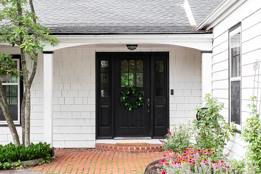 Plainfield, IL, USA - July 15, 2021: A beautiful farmhouse ranch with white siding and a black front door. Detail shot of the front door.