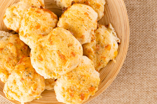 Fresh baked cheese biscuits close-up on a wooden plate, flat lay
