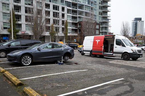 Seattle, USA - Dec 2, 2022: A  gas powered Mercedes-Benz Tesla repair vehicle changing a tire on a EV Tesla mid day in downtown.