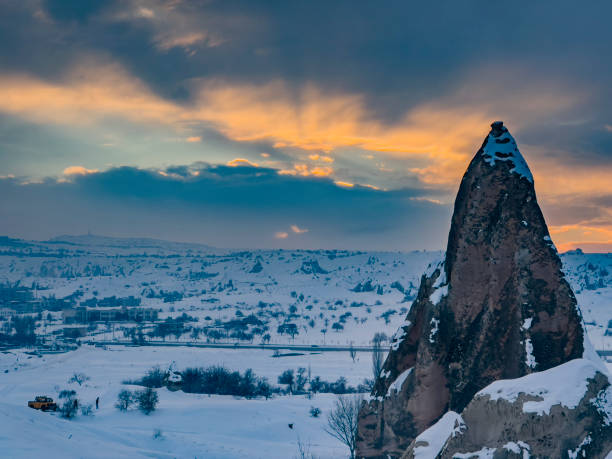 Travel destination concept: Volcanic rock formation in Cappadocia, Central Anatolia, Turkey. Historical area covered with snow. Winter landscape with rock hoodoos. Day tourist activities, poster background with copy space.