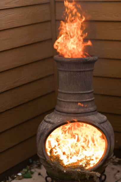 istock Rustic Chiminea Fire Pit Flaming with Cut Christmas Tree Pine Wood & Needles on a Cold Winter Day in South Florida 1458100569