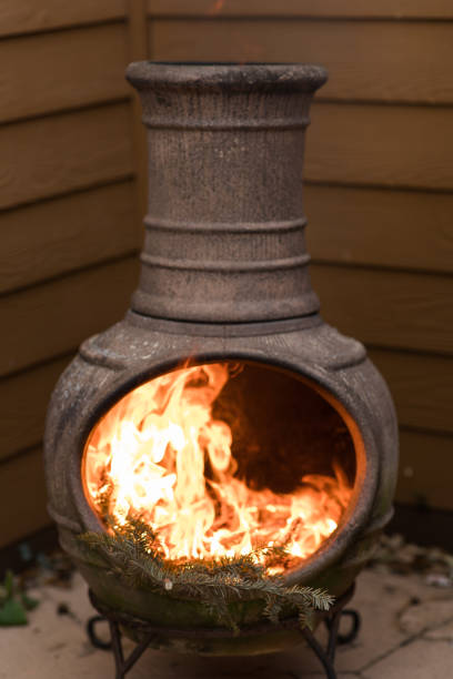 istock Rustic Chiminea Fire Pit Flaming with Cut Christmas Tree Pine Wood & Needles on a Cold Winter Day in South Florida 1458100780