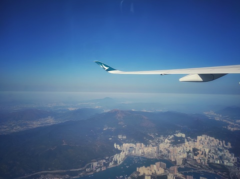 Hong Kong, January 2023  : View of the wings of a Cathay Pacific airplane through the window of the plane, with the sky in the background.