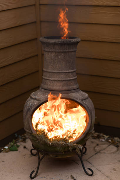 istock Rustic Chiminea Fire Pit Flaming with Cut Christmas Tree Pine Wood & Needles on a Cold Winter Day in South Florida 1458101647