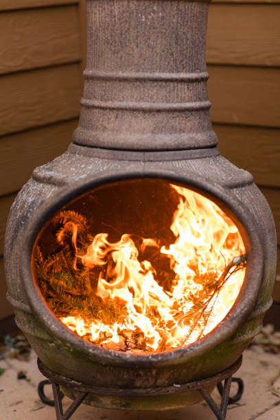 istock Rustic Chiminea Fire Pit Flaming with Cut Christmas Tree Pine Wood & Needles on a Cold Winter Day in South Florida 1458101842
