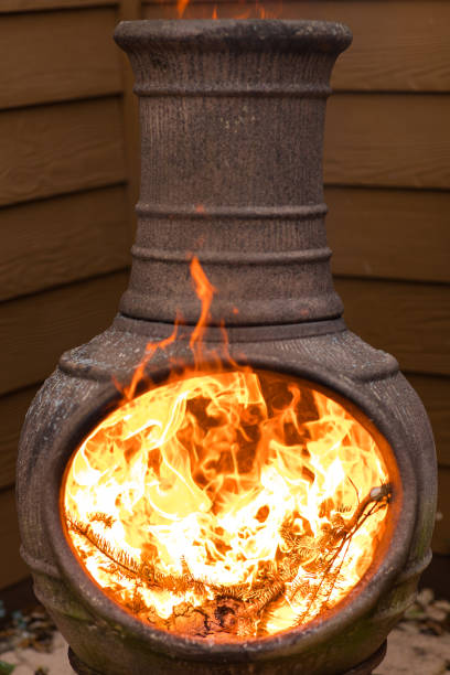 istock Rustic Chiminea Fire Pit Flaming with Cut Christmas Tree Pine Wood & Needles on a Cold Winter Day in South Florida 1458101844