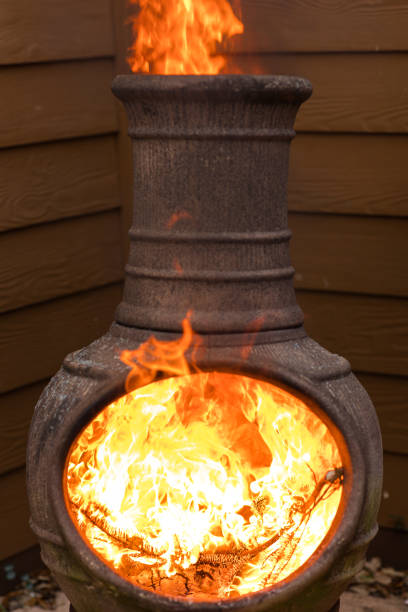 istock Rustic Chiminea Fire Pit Flaming with Cut Christmas Tree Pine Wood & Needles on a Cold Winter Day in South Florida 1458102046