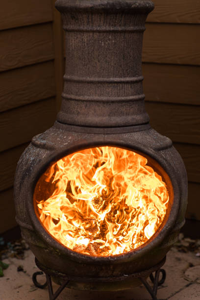 istock Rustic Chiminea Fire Pit Flaming with Cut Christmas Tree Pine Wood & Needles on a Cold Winter Day in South Florida 1458102384