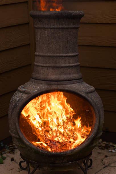 istock Rustic Chiminea Fire Pit Flaming with Cut Christmas Tree Pine Wood & Needles on a Cold Winter Day in South Florida 1458103127