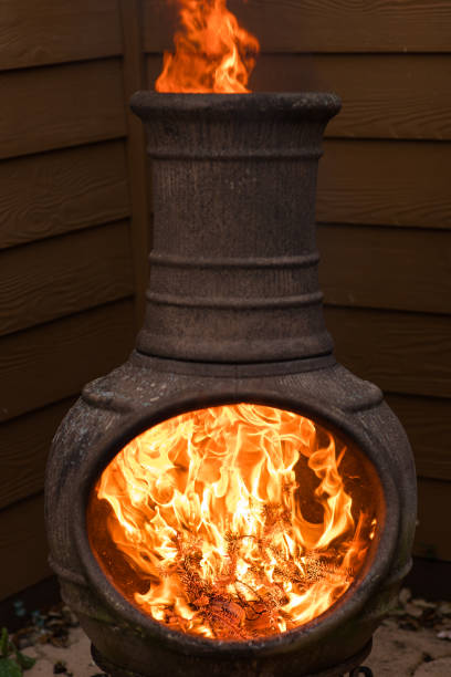 istock Rustic Chiminea Fire Pit Flaming with Cut Christmas Tree Pine Wood & Needles on a Cold Winter Day in South Florida 1458103130