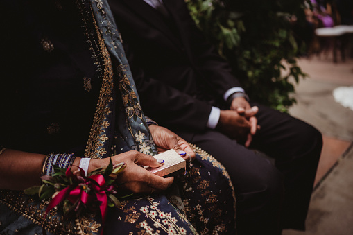 Parents of the groom in Indian formalwear at a wedding ceremony holding a gift box