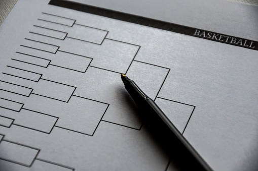 Blank basketball bracket grid on white paper with pen laying on top