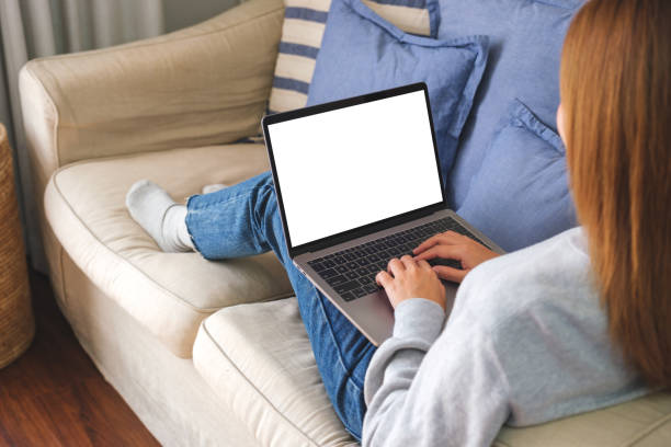 istock Mockup image of a woman working and typing on laptop computer with blank screen on sofa at home 1458108148