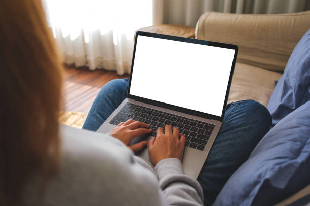 istock Mockup image of a woman working and typing on laptop computer with blank screen on sofa at home 1458108161