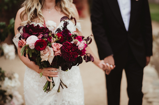 Bride and groom with bouquet of flowers walking hand in hand