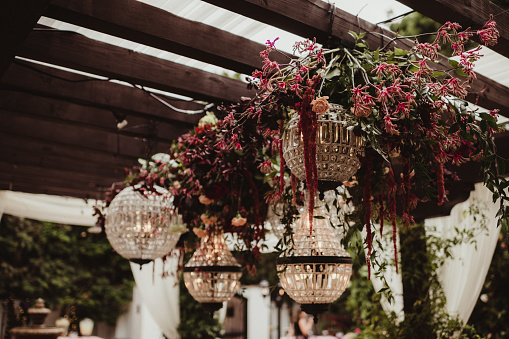 Round elegant chandeliers hanging from a pergola at a wedding reception