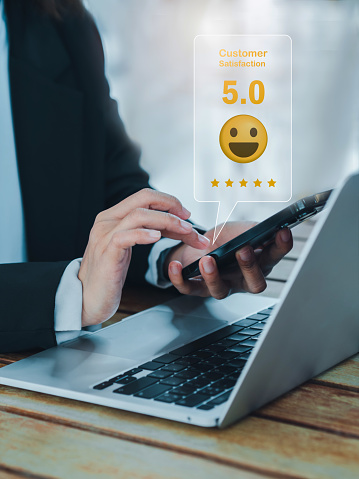 Customer satisfaction, review, feedback and survey concepts. The User giving five stars rating with smile face icon to service experience, business ranking on online app by smart mobile phone.