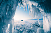 Ice cave with icicles on Baikal lake at sunset. Winter Baikal lake, Siberia, Russia