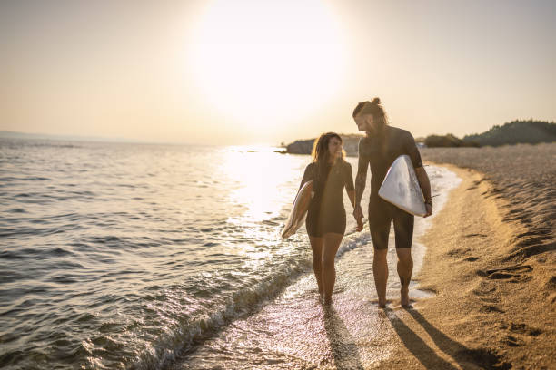 istock Surfers walking on the beach at sunset 1458126015
