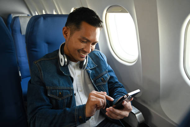 istock Smiling man passengers hands typing text on smart phone while sitting near window in an airplane. 1458126202