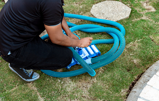 Man connecting the handle on the pool vacuum. Suction equipment connection for swimming pool, Pool suction hose installation. Person connecting pool hose handle