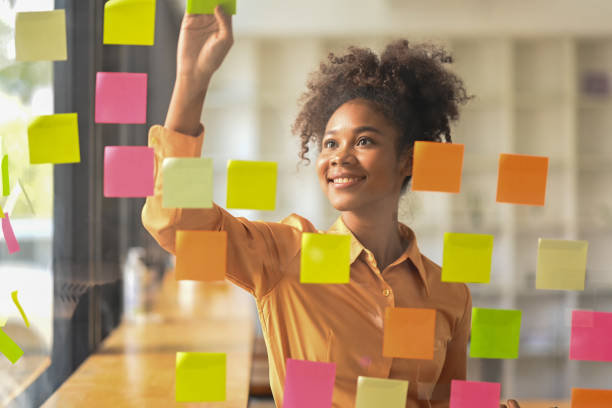 istock African American female team leader putting sticker notes to share idea for startup project on glass board in office. 1458126774