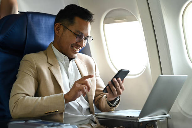 istock Smart millennial businessman passengers hands typing text on smart phone while sitting near window in an airplane. 1458127725