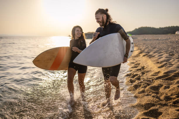 istock Couple of surfers at sunset 1458130068