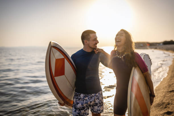 istock Surfer couple on the beach with surfing boards 1458131118