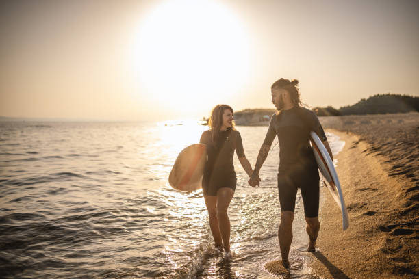 istock Surfers walking on the beach at sunset 1458133134