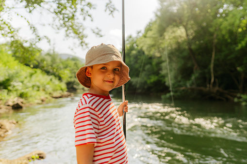 Portrait of a little boy fishing on the riverbank