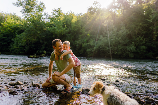 Photo of father and son, exploring together beautiful nature by the river