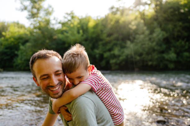 Photo of father and son, exploring together beautiful nature by the river