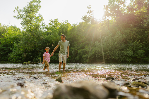 Photo of father and son, exploring together beautiful nature by the river