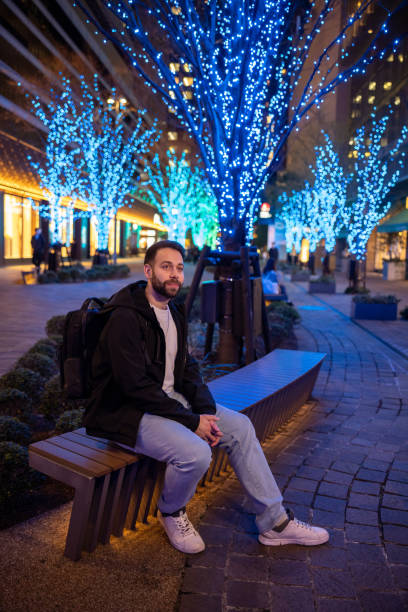 istock Young tourist sitting on bench under blue Christmas lights 1458143509