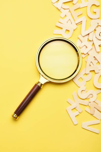 istock Magnifying glass with wooden alphabets on the yellow background 1458143907