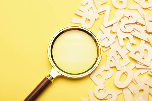 istock Magnifying glass with wooden alphabets on the yellow background 1458143932