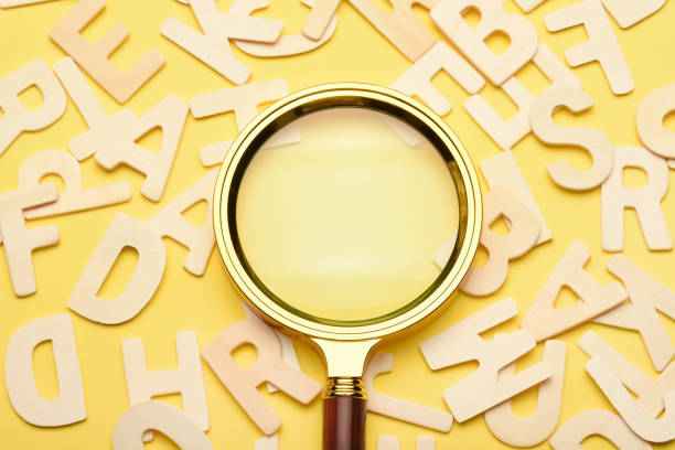 istock Magnifying glass with wooden alphabets on the yellow background 1458143998