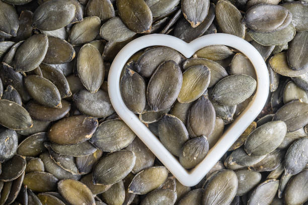 Green pumpkin seeds together with a heart shape as pattern background stock photo