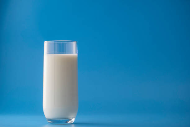 istock Glass of white milk isolated on blue background 1458144511