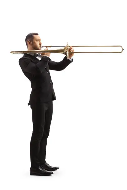 Full length profile shot of an elegant male musician playing a trombone isolated on white background