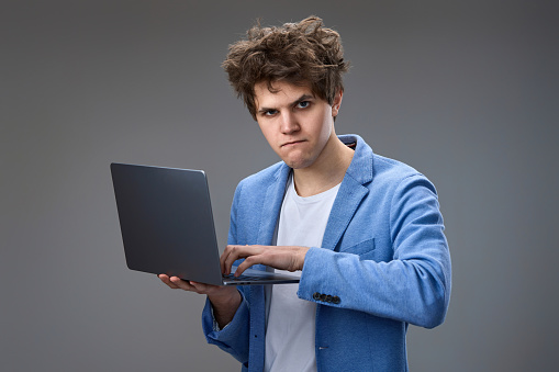 Funny and crazy caucasian geek man with laptop on gray background