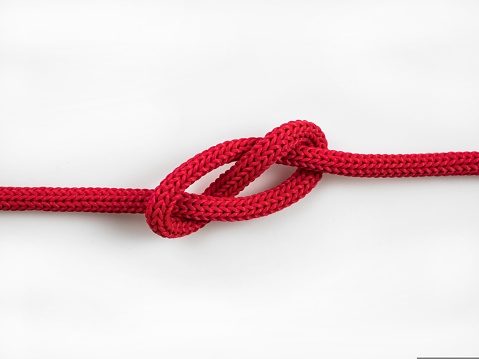 closeup of a red rope knot on a white background