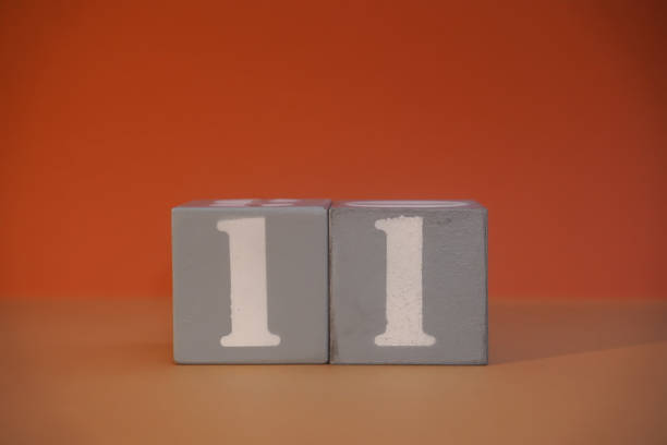Number 11 on wooden grey cubes close-up. Concept of date time. Math concept. Copy space for text or event. White numbers 11 on building blocks, orange background. Educational cubes. Blurred background número 11 en cubos grises de madera en primer plano. concepto de fecha y hora. concepto matemático. copie el espacio para el texto o el evento. números blancos 11 en bloques de construcción, fondo naranja. cubos educativos. fondo borroso