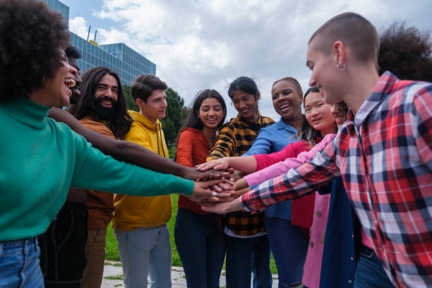 istock Group of ethnically diverse young people joining hands 1458160157