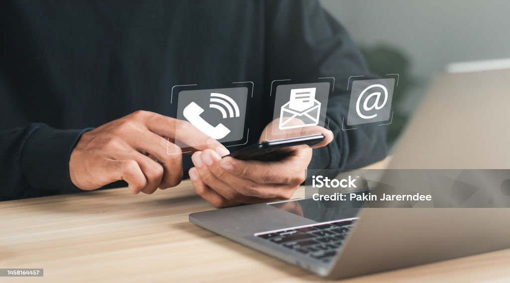 Businessman using laptop and smartphone with contact icons on virtual screen. searching web, browsing information, Contact us or Customer support hotline people connect. Contact Us Stock Photo