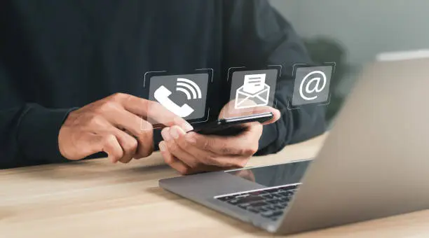 Photo of Businessman using laptop and smartphone with contact icons on virtual screen. searching web, browsing information, Contact us or Customer support hotline people connect.