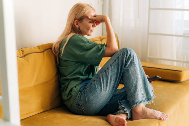 우울한 슬픈 중년 여자가 집에서 소파에 앉아 있다. - frustration emotional stress surprise women 뉴스 사진 이미지