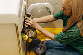 A woman loads dirty laundry into the washing machine.